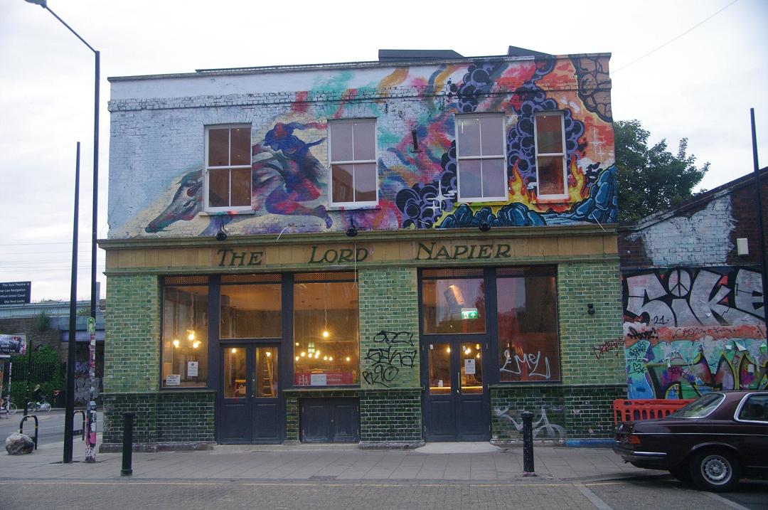 The Lord Napier pub on White Post Lane in Hackney Wick, its upper floor covered in a colourful mural above a green tiled ground floor.