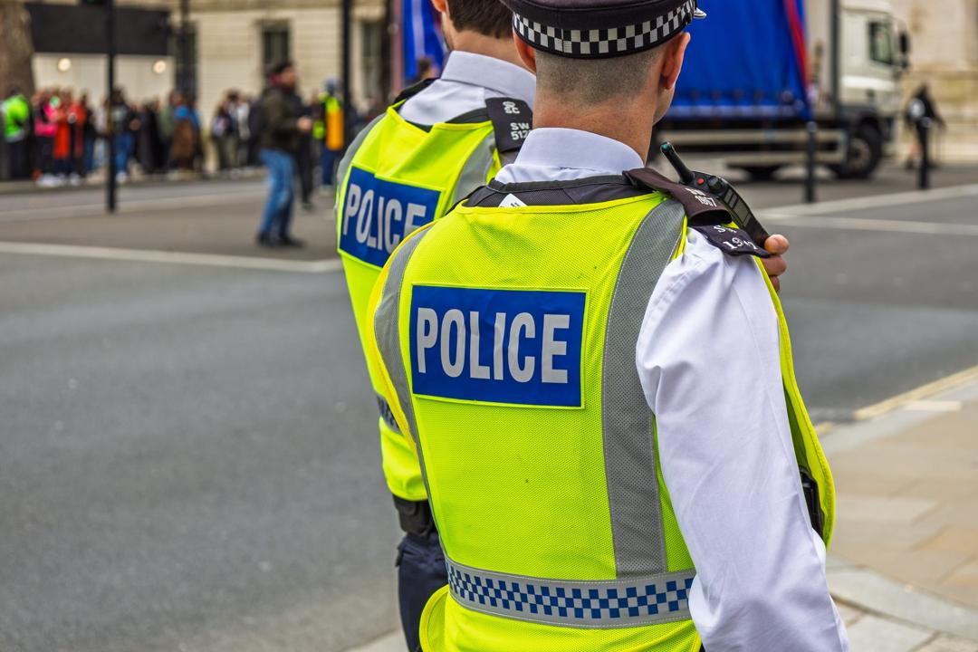 Two police officers in high-visibility vests on a city street, seen from behind